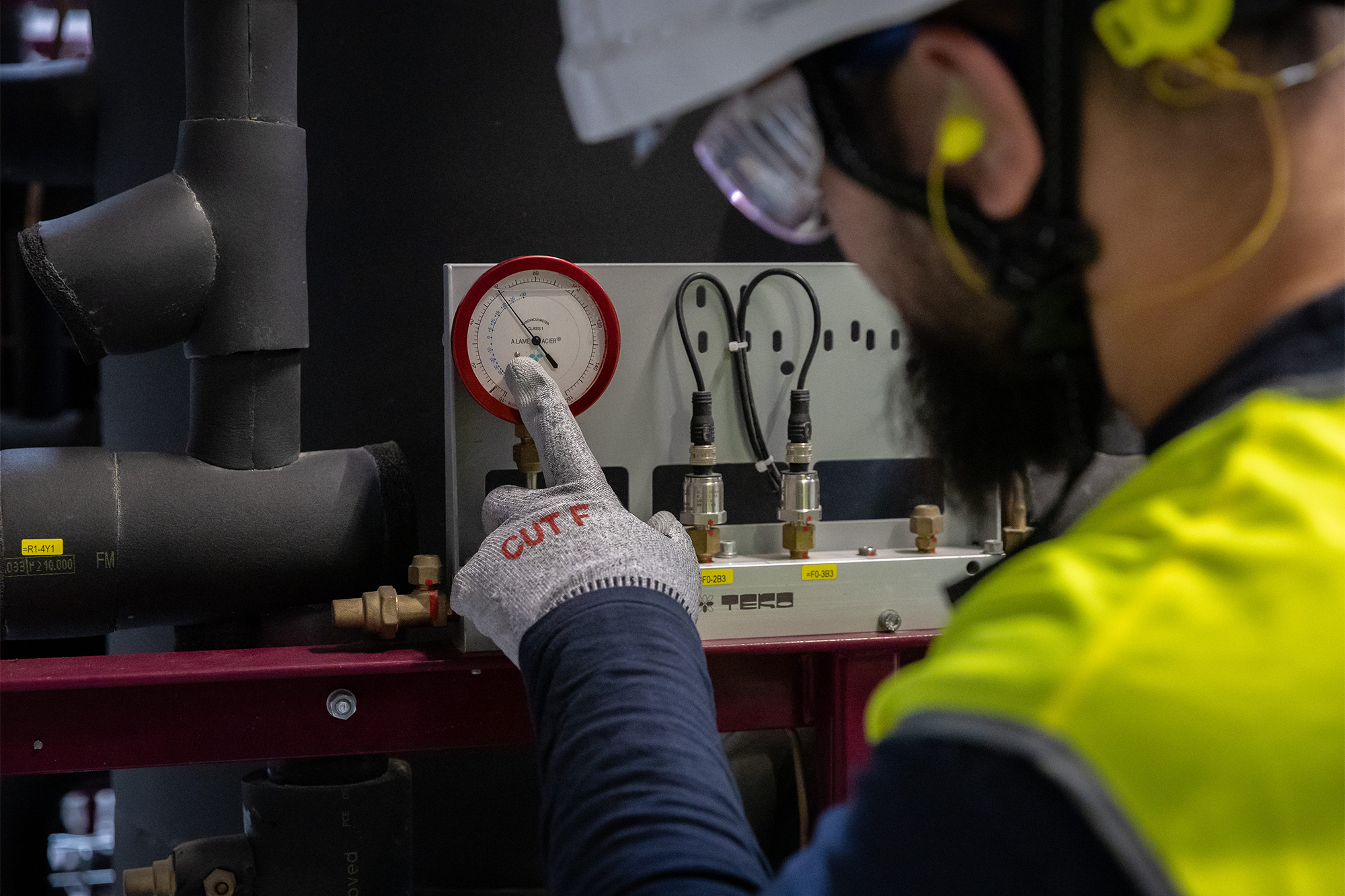 Frigoriste effectuant une tâche de contrôle sur un manomètre sur une installation froide 